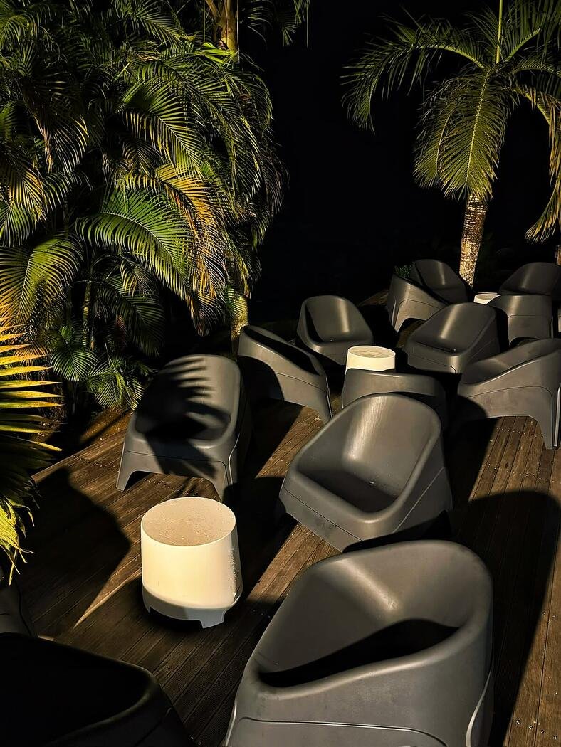 Coin lounge éclairé sous les palmiers à la nuit tombée