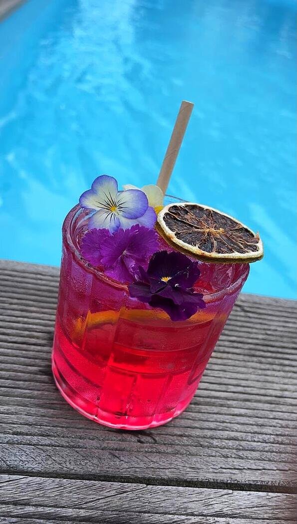 Cocktail signature aux fleurs servi au bord de la piscine